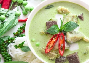 Green curry creamy coconut milk with chicken , the Popular Thai food called Gaeng Keow Wan Gai on wooden table