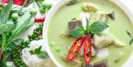 Green curry creamy coconut milk with chicken , the Popular Thai food called Gaeng Keow Wan Gai on wooden table
